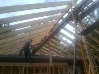 Rafters going up over a new addition with a worker on the wall in Fair Lawn
