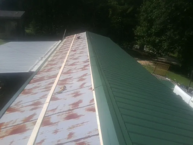 Old rusted panels beside newly installed green metal roofing — Wind Damage Roof Repair by Roofing Brothers in Fair Lawn