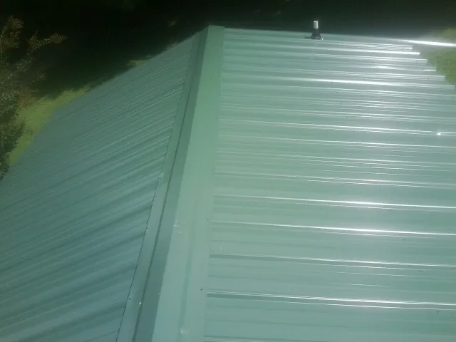 New green metal panels meeting at the ridge of a roof — Flat Roof Repair work by our crew in Fair Lawn