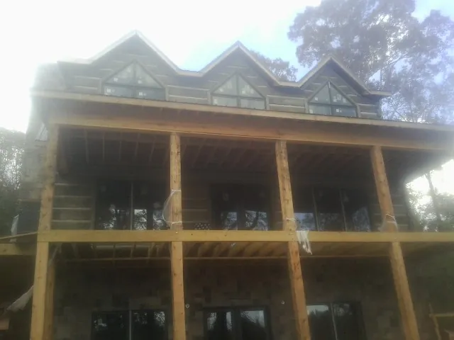 Dormers and porch framing on a large log home under construction — Roof Coating work by our crew in Fair Lawn
