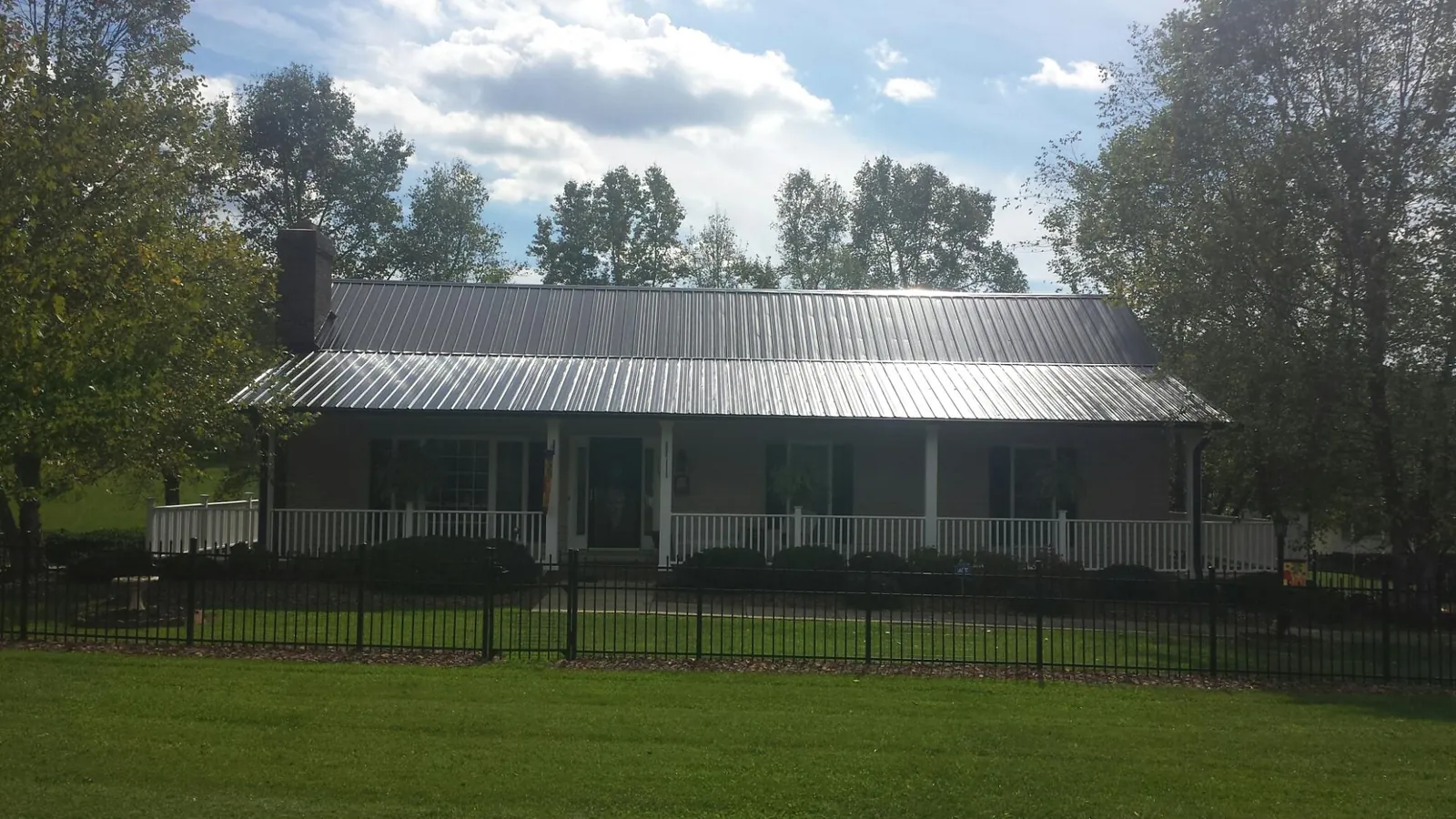 Gray metal roof on a brick ranch with a full width front porch — Gutter Guard Installation work by our crew in Fair Lawn