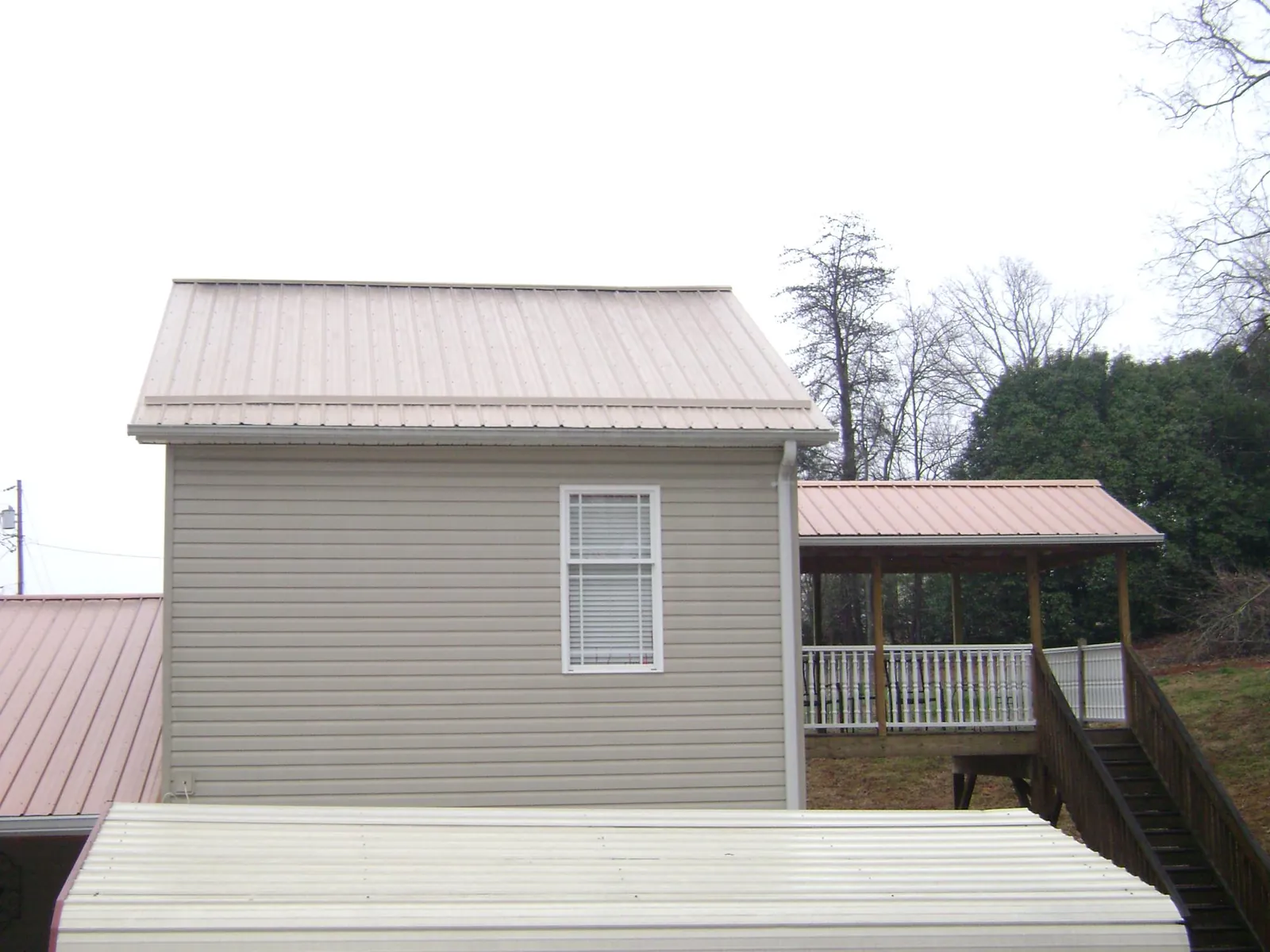 Tan metal roofs on a two story addition and attached porch, from a Roof Replacement job in Fair Lawn