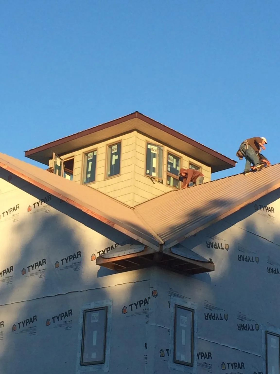 Roofers working around a rooftop cupola on a new metal roof at sunset — Roof Waterproofing in Fair Lawn by Roofing Brothers